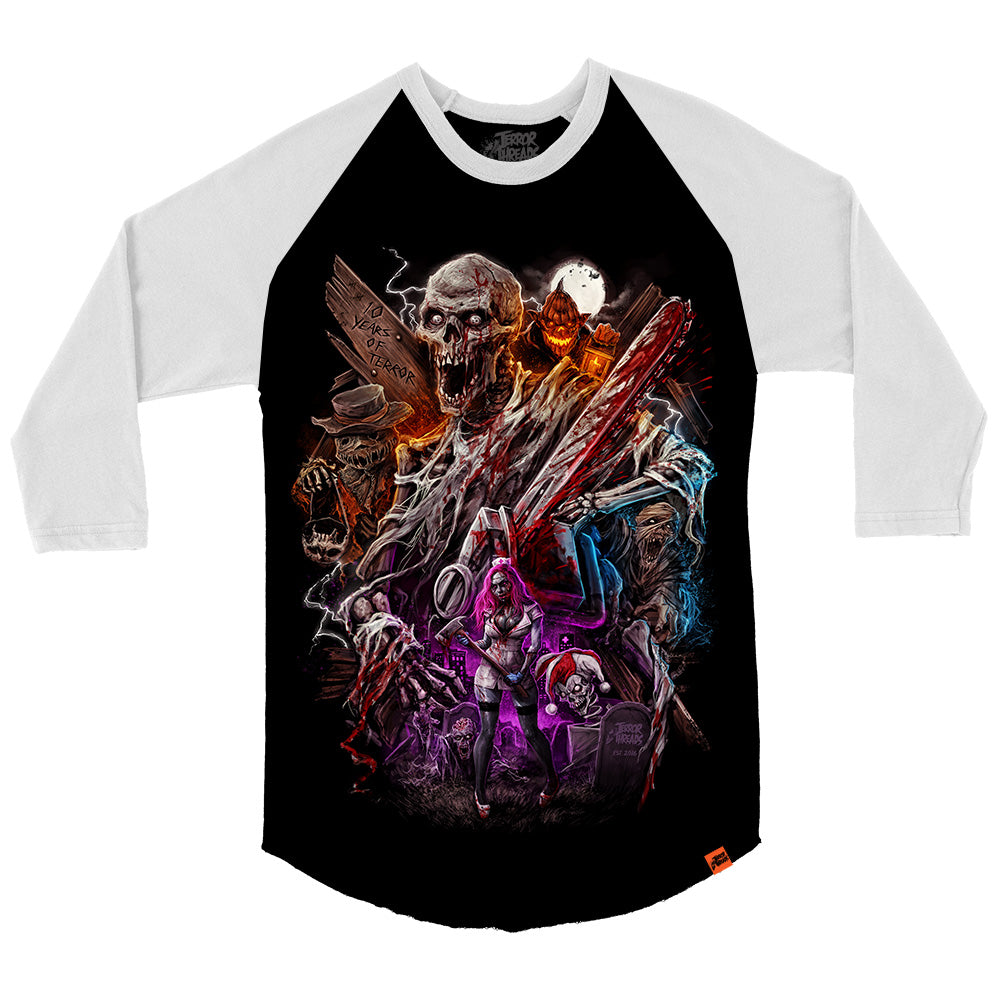 Black and white raglan baseball tee featuring a large, detailed horror collage design with a screaming skeletal figure holding a blood-covered chainsaw at the center, surrounded by a scarecrow, glowing jack-o’-lantern, masked characters, lightning effects, and a pink-haired female character, with “10 Years of Terror” carved into wood in the background.
