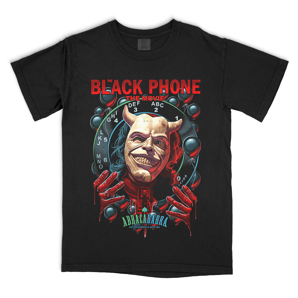 The Black Phone Abracadabra T-Shirt on a black Comfort Colors Tee featuring The Grabber in his horned mask surrounded by black balloons and a rotary phone dial