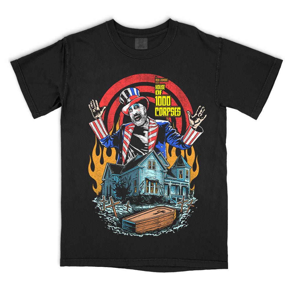 House Of 1000 Corpses Bless This House T-Shirt on black Comfort Colors tee featuring Captain Spaulding above the Firefly house with flames, graves, and a coffin.