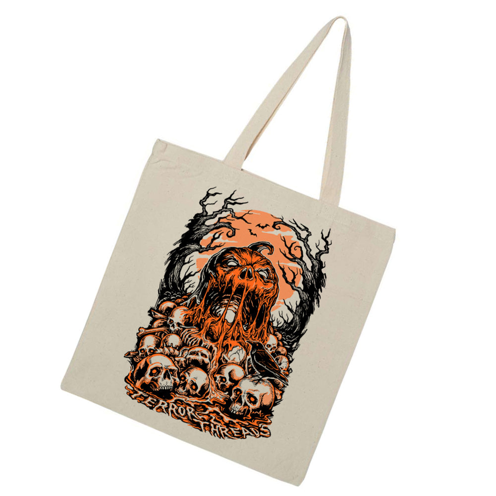 Terror Threads Original Bone Deep natural canvas tote bag featuring a terrifying skeletal creature rising from a pile of skulls beneath an orange moon and twisted trees.