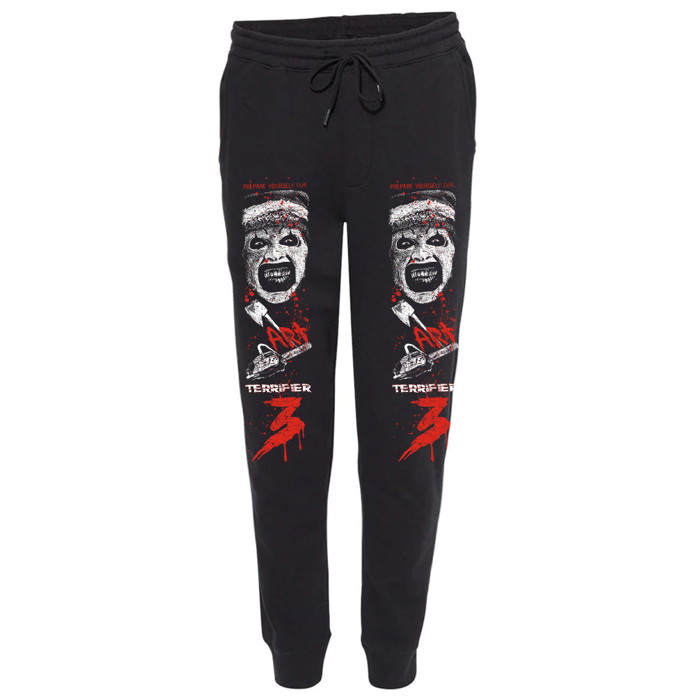 Officially licensed Terrifier 3 Unrated Terror black joggers featuring Art the Clown, bloody red and white chainsaw artwork, and Terrifier 3 graphics printed down both legs.
