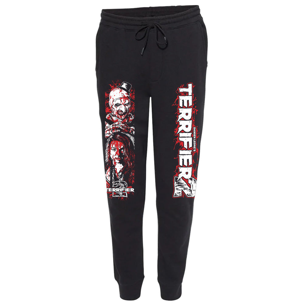 Officially licensed Terrifier 2 Work Of Art black joggers featuring Art the Clown and Sienna Shaw artwork on one leg and bold vertical Terrifier 2 lettering on the other in red and white.